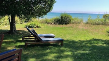 Relax on the deck with a clear sea view, surrounded by lush greenery and a shaded area perfect for unwinding.