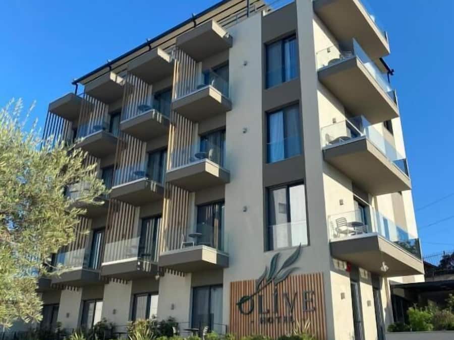 Un moderno edificio de apartamentos de varios pisos con balcones, fachada de madera y una escalera que conduce a la entrada.