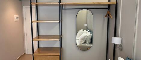 Un dormitorio con cama, un armario de madera, un espejo y una lámpara de noche.