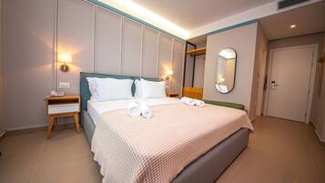A hotel room with a large bed, bedside lamps, a mirror, and a wooden nightstand.