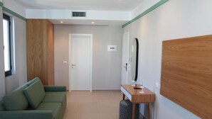 A modern room with a green sofa, a wooden accent wall, a small table with a mirror, and a door leading to another room. - Olive Hotel Ksamil (Ksamil)