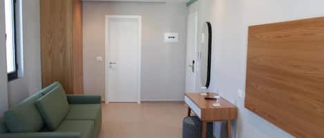 Una habitación moderna con un sofá verde, un muro decorativo de madera, una mesita con un espejo y una puerta que da a otra habitación.