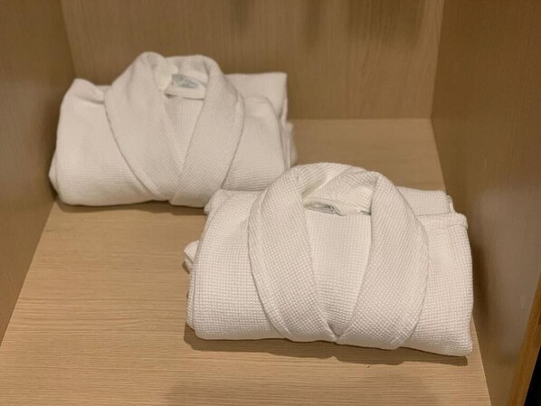 Two neatly folded white robes on a wooden bench.