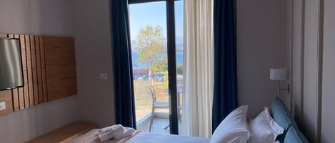 Une chambre d’hôtel avec un lit, un téléviseur fixé au mur et une vue sur l’extérieur grâce à une grande fenêtre.