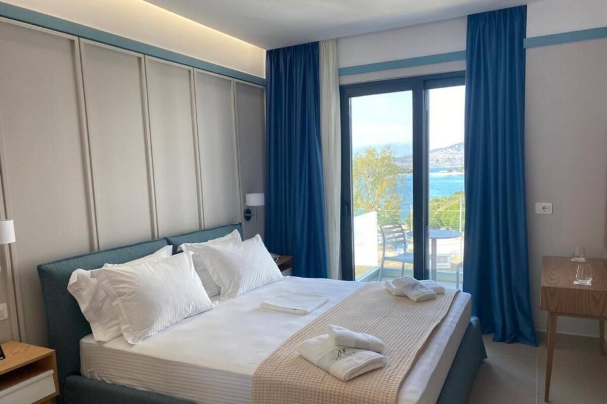 A hotel room with a large bed, a view of the sea, and a small table with a glass.
