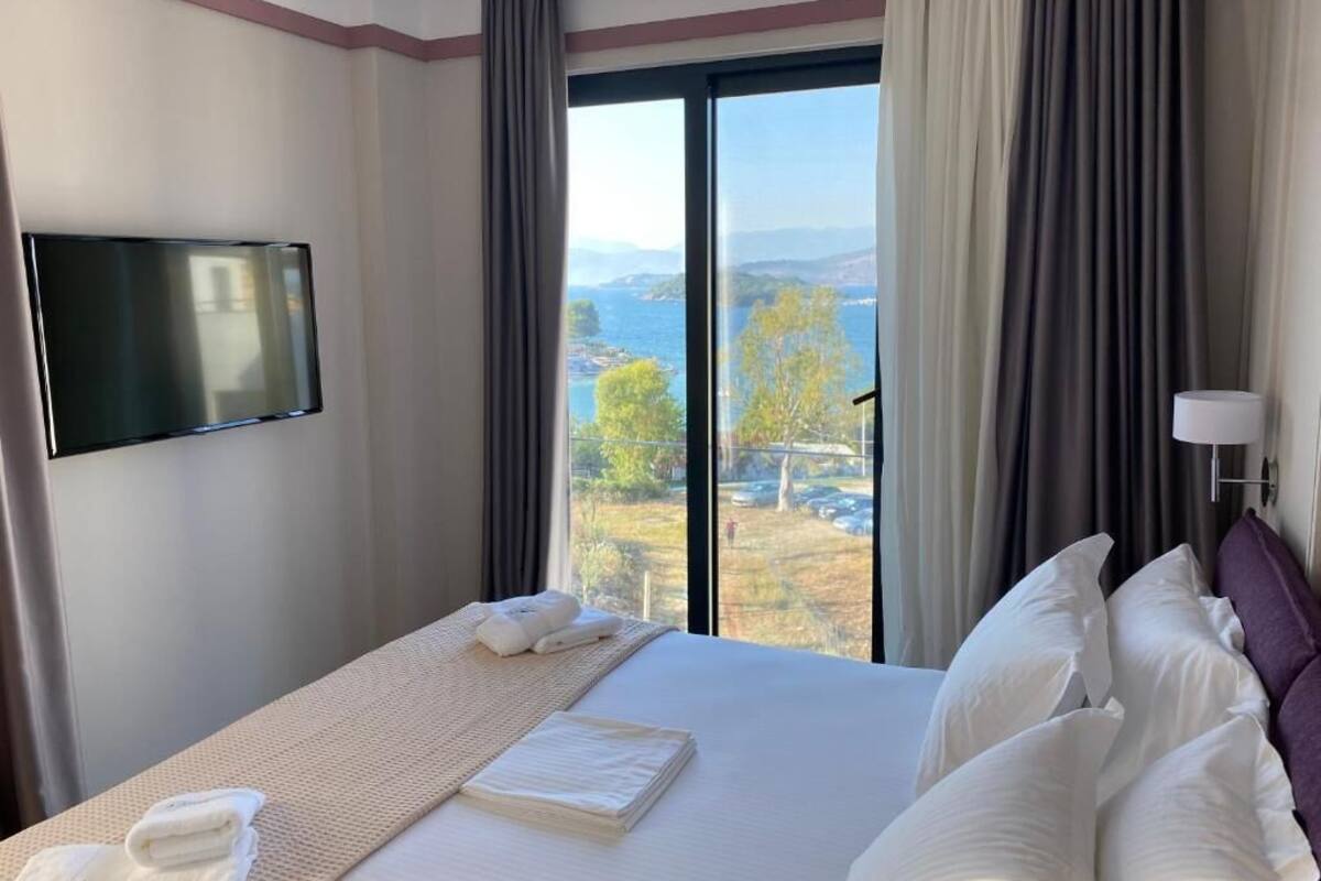 A hotel room with a bed, a TV mounted on the wall, and a view of the outdoors.