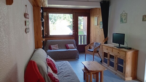 Um quarto aconchegante com um sofá de madeira, uma mesa pequena e uma TV em um armário de madeira.