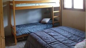 Quarto pequeno e compacto com uma beliche e uma cama de solteiro.
