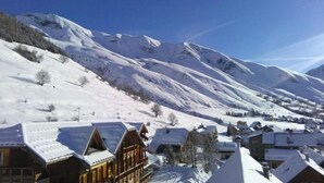 Uma aldeia montanhosa coberta de neve com edifícios de madeira tradicionais e um céu azul límpido.