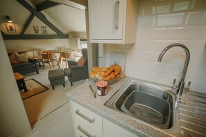 A kitchen with a granite countertop, a stainless steel sink, and a bowl of croissants.