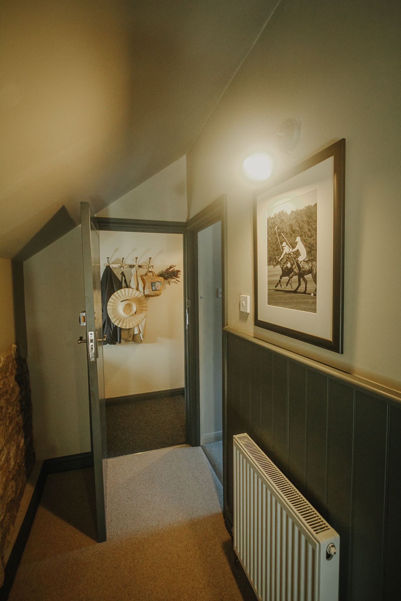 A hallway with a radiator, a framed picture on the wall, and a door leading to a bathroom.