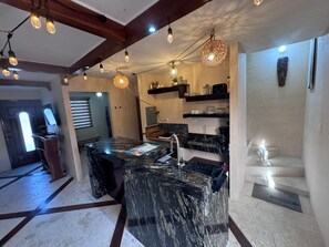 Una cocina moderna con una isla de mármol, iluminación colgante y estanterías empotradas.