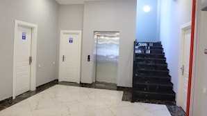A spacious hallway with marble flooring, white doors, and a black staircase. - Maajid Quba Hotel&Restaurant Sanatorium (Quba)