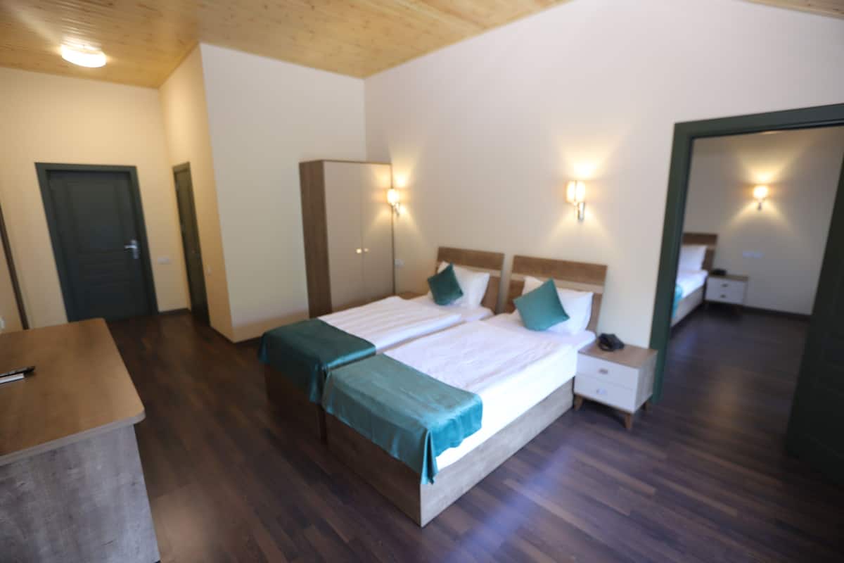A bedroom with two beds, bedside tables, a wardrobe, and wall-mounted lights.