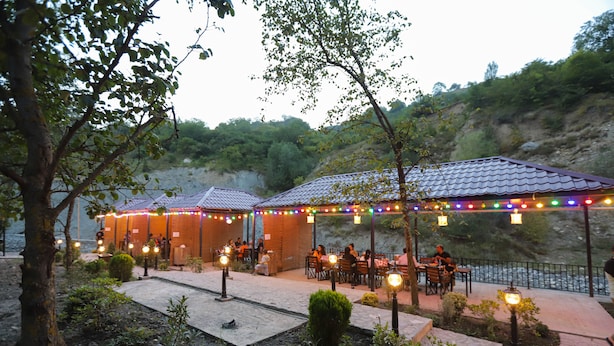 An outdoor restaurant with tables and chairs, string lights, and a view of a river. - Maajid Quba Hotel&Restaurant Sanatorium (Quba)