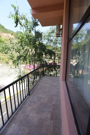 A balcony with a metal railing, a tiled floor, and a view of trees and a building in the background. - Maajid Quba Hotel&Restaurant Sanatorium (Quba)