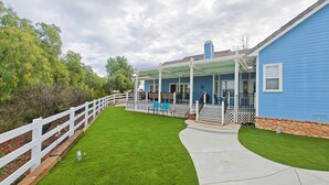 Een blauw huis met een overdekte veranda, een witte hek en een groen gazon.
