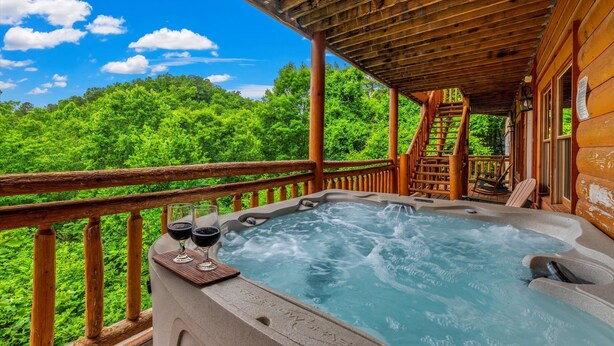 A hot tub on a wooden deck with a view of lush greenery. - Large Luxury Cabin Near Pigeon Forge | Indoor Pool, Theater, Sleeps 56 (Sevierville)