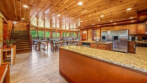 A spacious kitchen with wooden cabinets, granite countertops, and stainless steel appliances. - Large Luxury Cabin Near Pigeon Forge | Indoor Pool, Theater, Sleeps 56 (Sevierville)