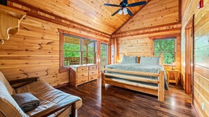 A wooden cabin bedroom with a bed, a bench, and a desk. - Large Luxury Cabin Near Pigeon Forge | Indoor Pool, Theater, Sleeps 56 (Sevierville)