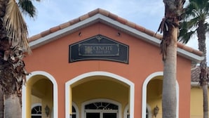 Un edificio con un letrero que dice "Cenote Day Spa" y una entrada simétrica con dos arcos y una puerta central.