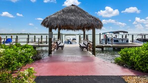 A pier leading to a thatched-roof gazebo with benches, surrounded by water and greenery. - Waterfront in Old Marco!  Beautiful unit!  Deluxe! (Marco Island)