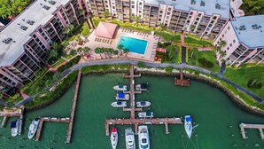 An aerial view of a marina with boats docked, surrounded by a residential building complex with a swimming pool and landscaped areas. - Waterfront in Old Marco!  Beautiful unit!  Deluxe! (Marco Island)