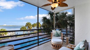 A balcony with a view of the sea, a pool, and outdoor furniture. - Waterfront in Old Marco!  Beautiful unit!  Deluxe! (Marco Island)