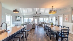 A spacious kitchen with a long island, bar stools, and a dining area with chairs and a table.