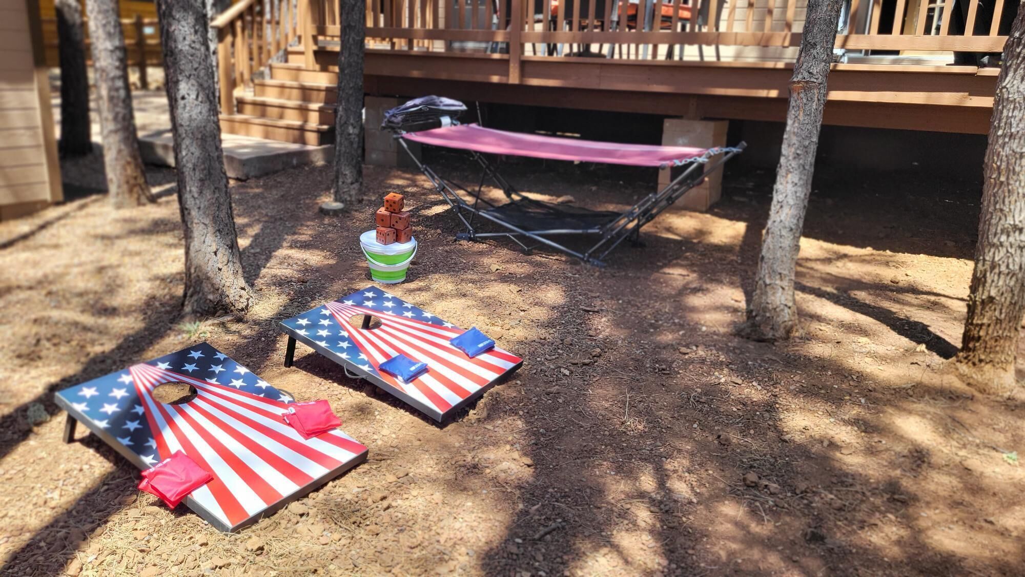 A deck with two American flag-themed lounge chairs, a folding chair, and a small table with dice.