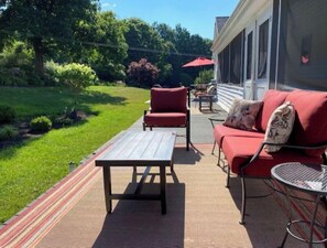 Relax on the patio surrounded by lush greenery and enjoy the comfort of a sofa and chairs.