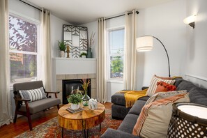 Una sala de estar con chimenea, un sofá, una silla y una mesa de centro.