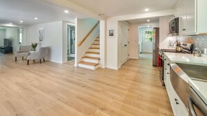 A spacious living area with a wooden floor, a staircase, and a kitchen with modern appliances. - Fun Getaway Lakehouse in the Hudson Valley (Craryville)