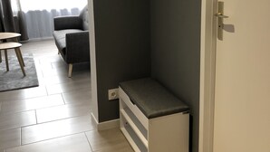 A modern room with a dark wall, a bench, a door with a handle, and a small table with a rug. - The Green cocoon: Above the Alsatian vineyard (Turckheim)