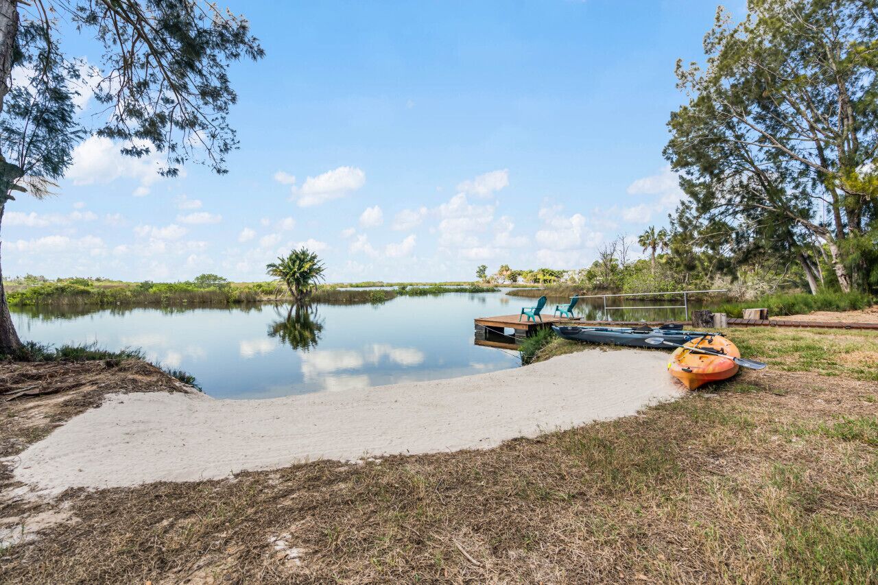 A tranquil lakeside setting with a dock, kayaks, and a small boat.