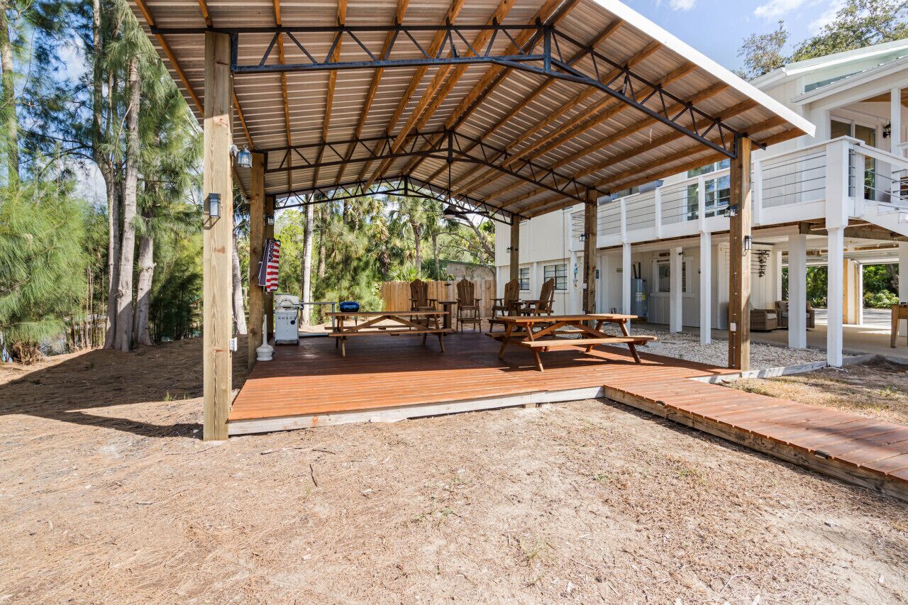 A covered outdoor area with picnic tables and a wooden deck.