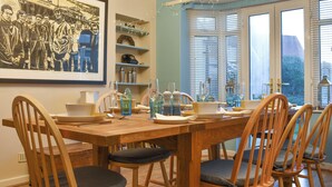 A dining area with a wooden table, chairs, and a large framed picture on the wall.