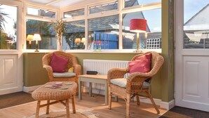 A sunroom with wicker chairs, a table, and a radiator.