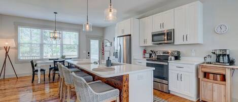A modern kitchen with white cabinets, stainless steel appliances, and a central island with bar stools.