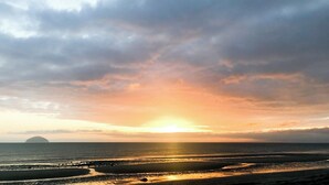 A beach with a sunset, calm sea, and distant island. - 2 bedroom accommodation in Girvan (Girvan)