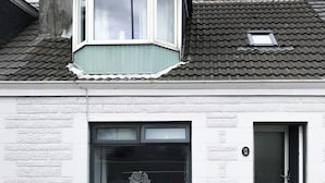 A white building with a bay window, a door with a number plate, and a small skylight. - 2 bedroom accommodation in Girvan (Girvan)