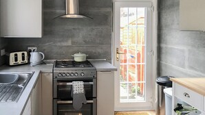 A compact kitchen with a gas stove, oven, and a toaster. - 2 bedroom accommodation in Girvan (Girvan)