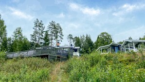 A modern house with a sloped roof, surrounded by dense greenery and tall trees. - Cozy home in Harmånger with lake view (Harmånger)