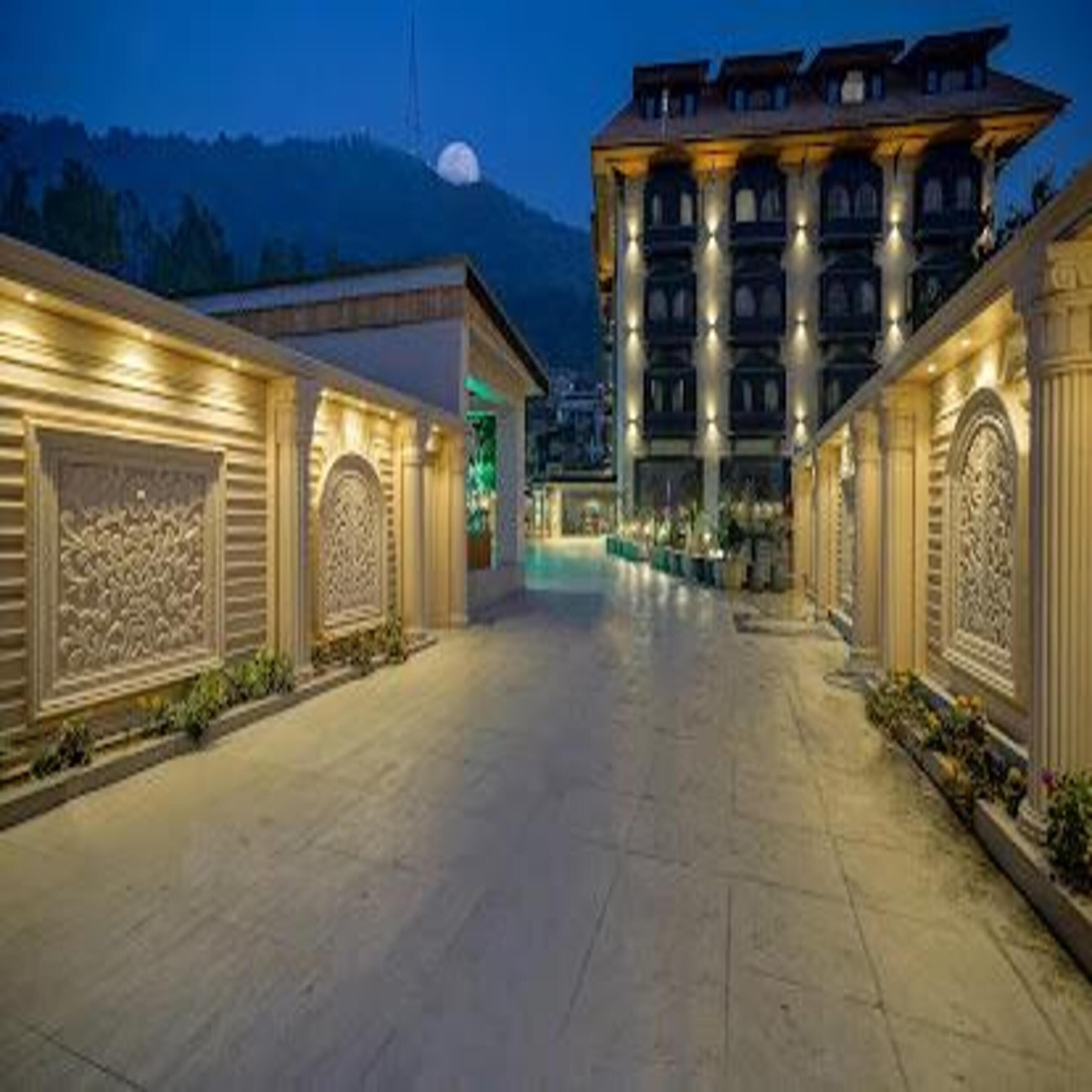A hotel corridor with ornate architectural details, a large building in the background, and a mountain view.