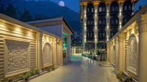 A hotel corridor with ornate architectural details, a large building in the background, and a mountain view. - Hotel Snowland Srinagar (Srinagar)