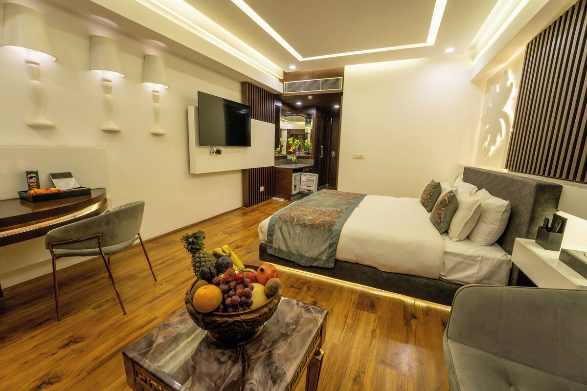A modern hotel room with a bed, a desk, and a seating area.
