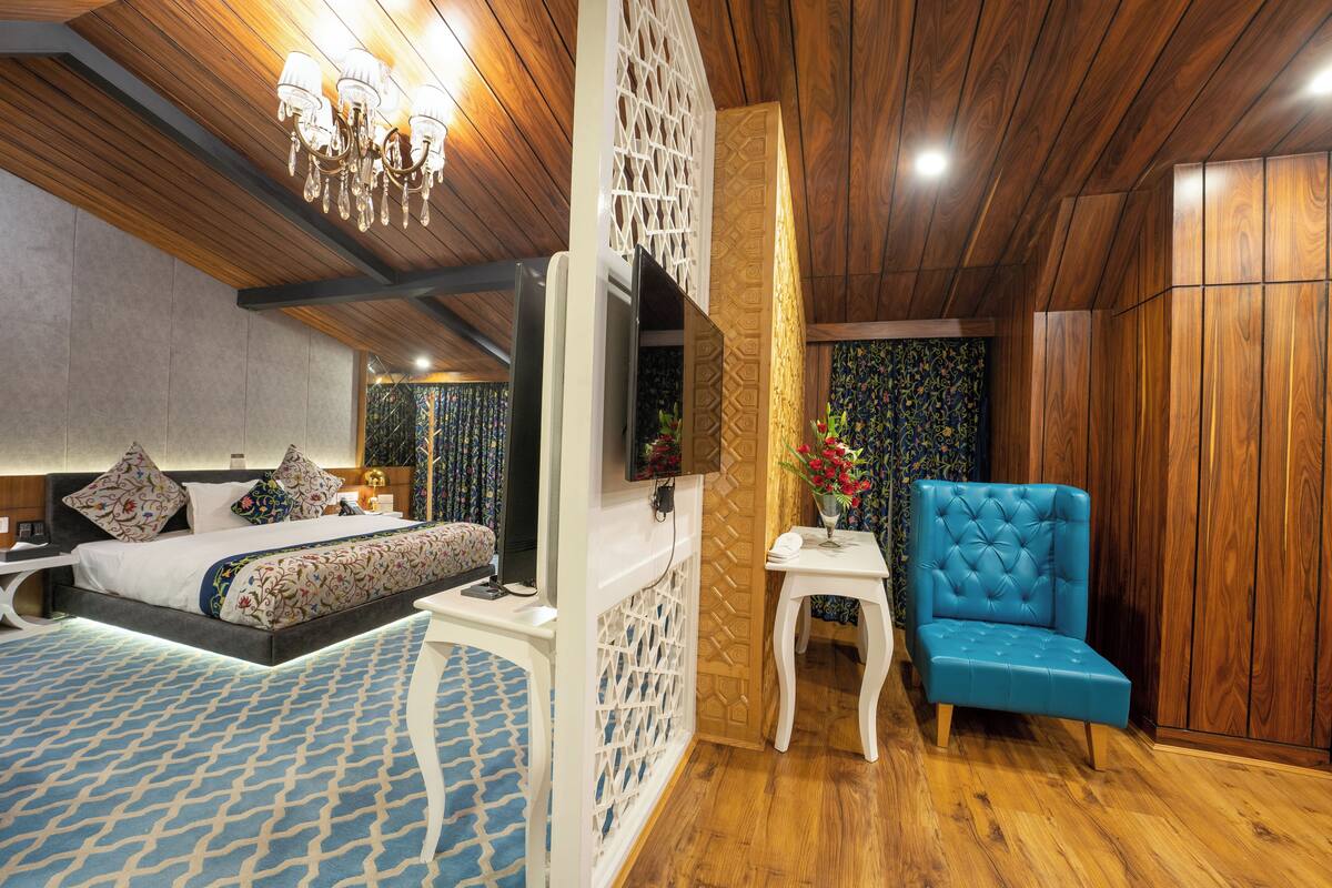 A bedroom with a bed, bedside table, TV, and a blue armchair.