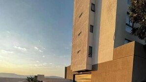 Un bâtiment moderne doté d’un toit plat, de grandes fenêtres et d’un chemin en béton menant à une entrée fermée par un portail.