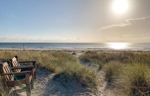 Ein Strand mit einer Holzbank und einem Weg zum Meer.