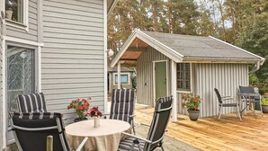 A wooden deck with outdoor furniture, including chairs and a table, and a small shed in the background. - 2 bedroom nice home in Borrby (Borrby)